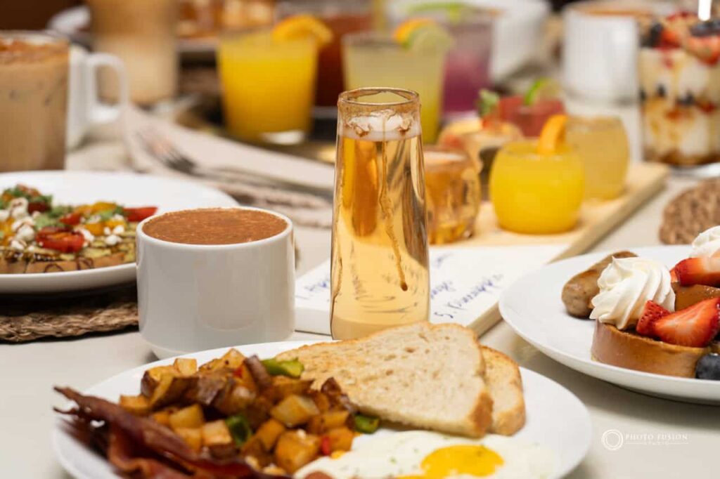 This is an image of an apple drink from Jojo's Coffehouse Breakfast & Brunch. There are other food and drink items around but the main focus is this drink.