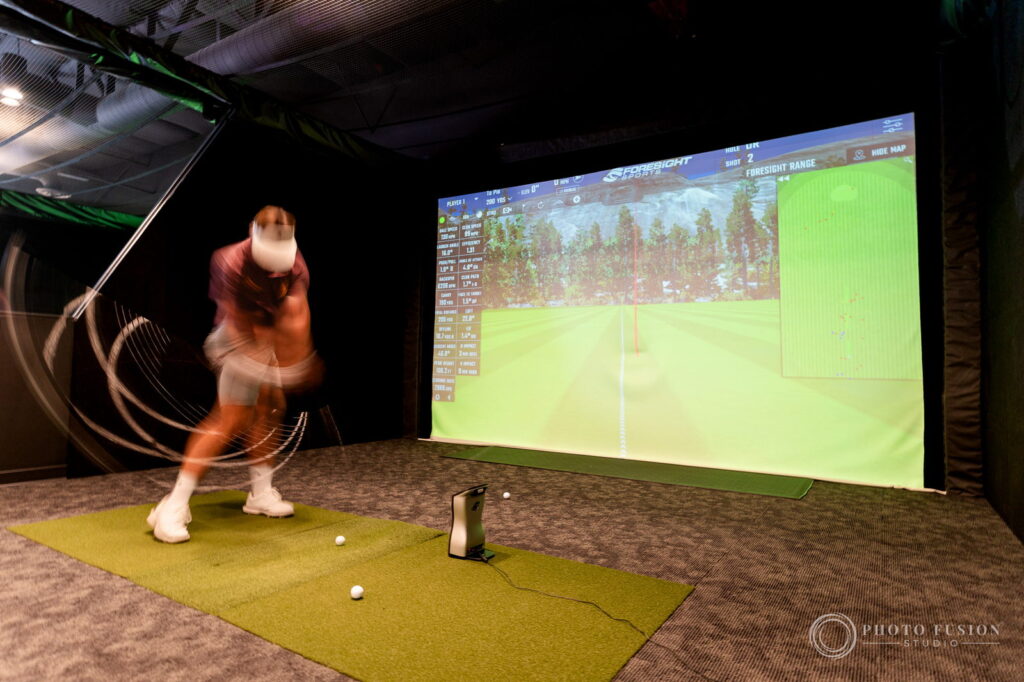 A long exposure captures the full arc of an ASU golfer's swing in front of a simulator screen