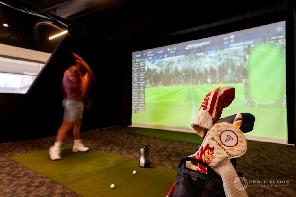 A long exposure blurs an ASU golfer's swing while a True Spec Sparky headcover stays sharp in the foreground