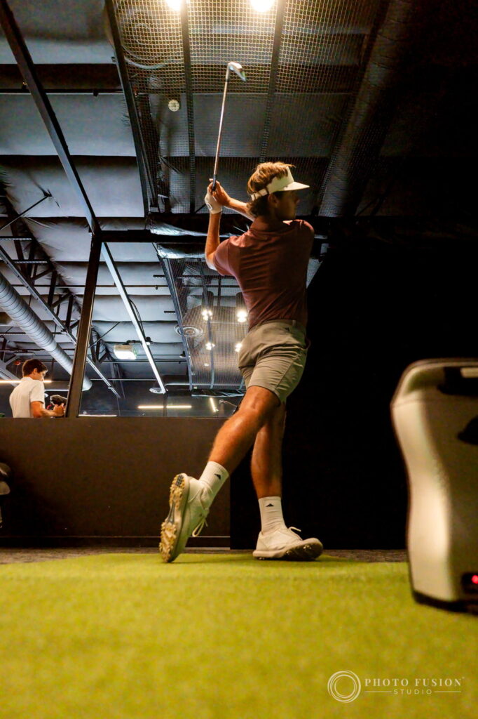 Low angle of an ASU men's golf player holding his finish after a full swing in the fitting bay
