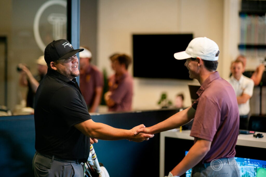 A True Spec Golf fitter and an ASU golfer shake hands and laugh at the end of a fitting