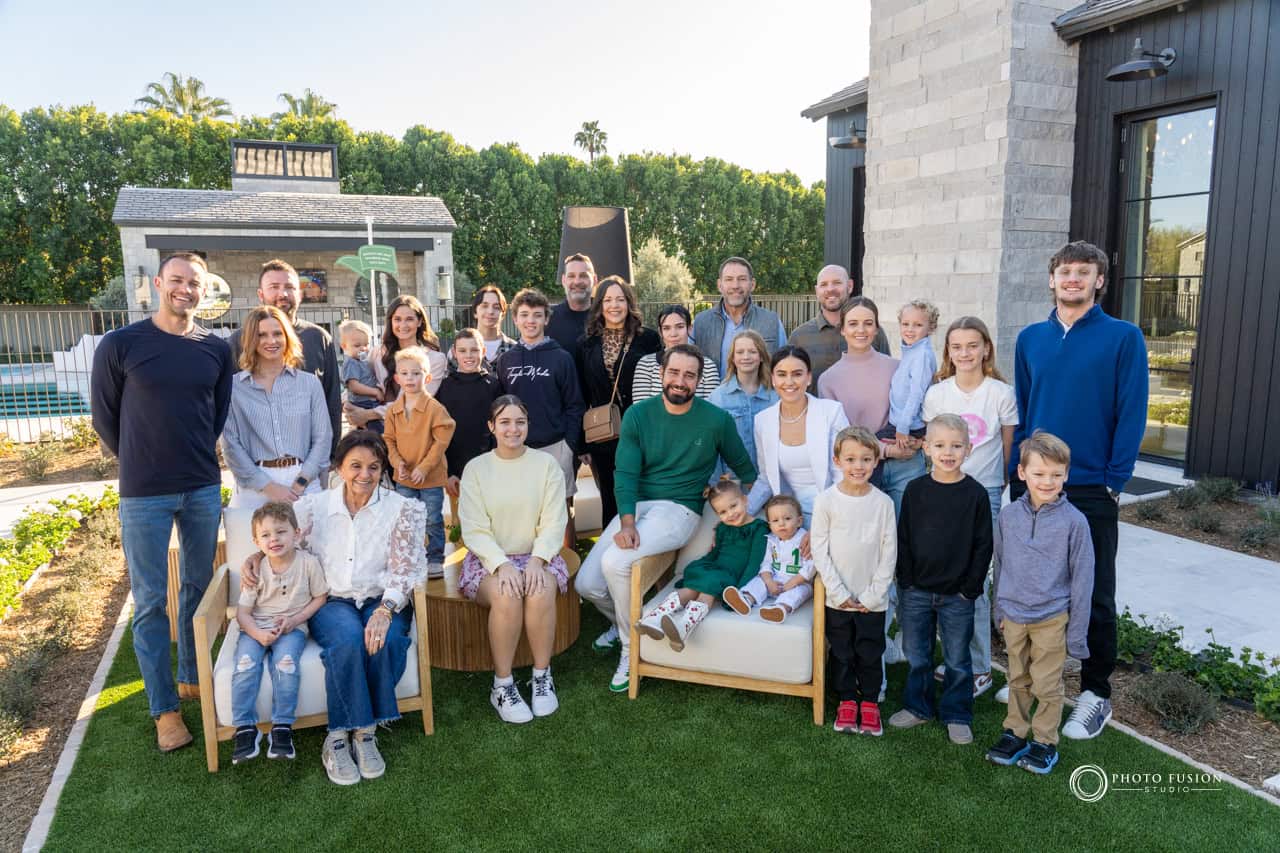 This is a big family photo that includes all the relatives that are relate to the birthday body who is in the caddie outfit. They are all gathered to celebrate the birthday boy's first birthday.