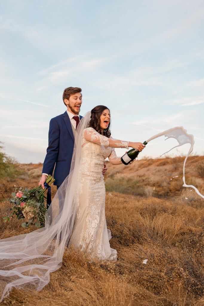 fun wedding couple popping champagne
