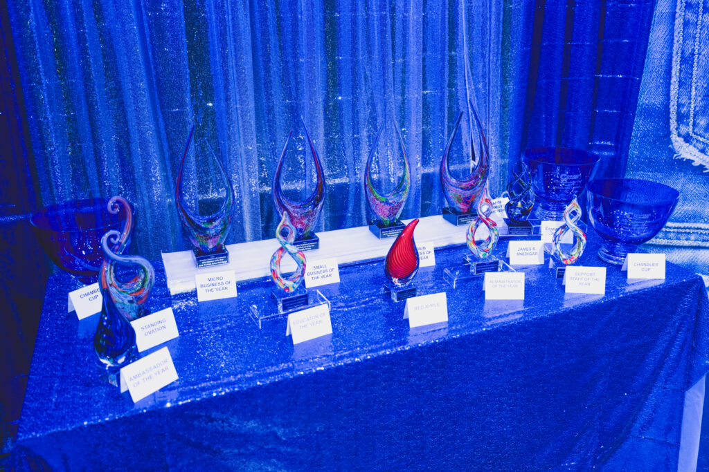 Glass trophies with category cards including Business of the Year on a sequined table at the Chandler Chamber Community Awards