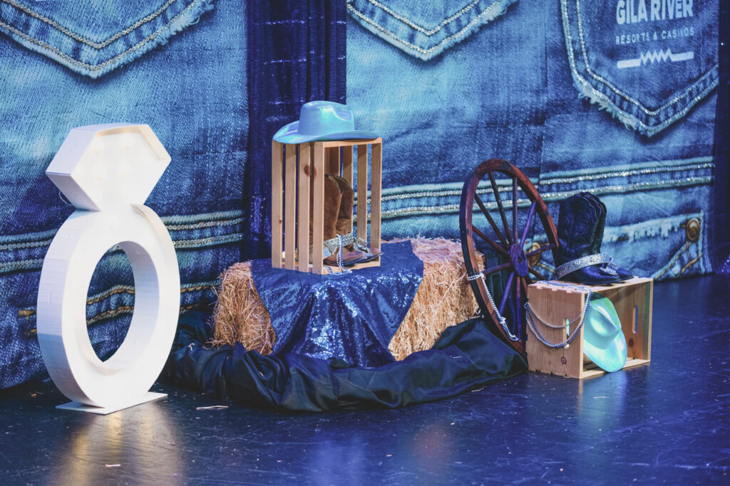 Western-themed stage decor with a giant diamond ring, hay bales, wagon wheel, and cowboy hats at the Chandler Chamber Awards