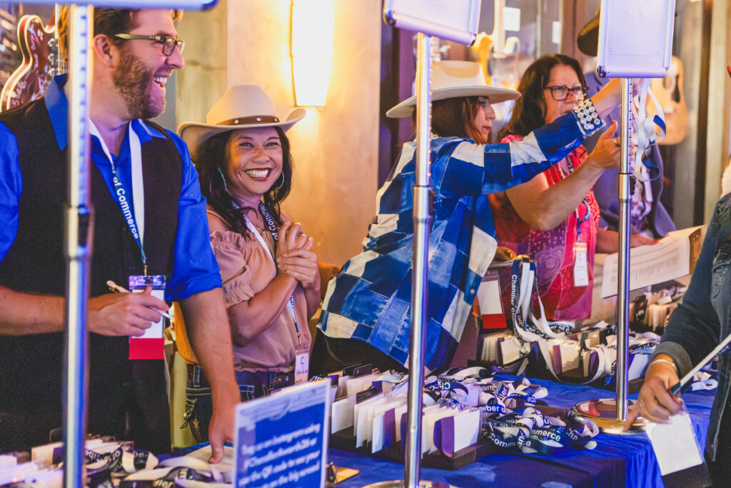 Smiling guests in denim and cowboy hats at the welcome table of the Chandler Chamber Community Awards
