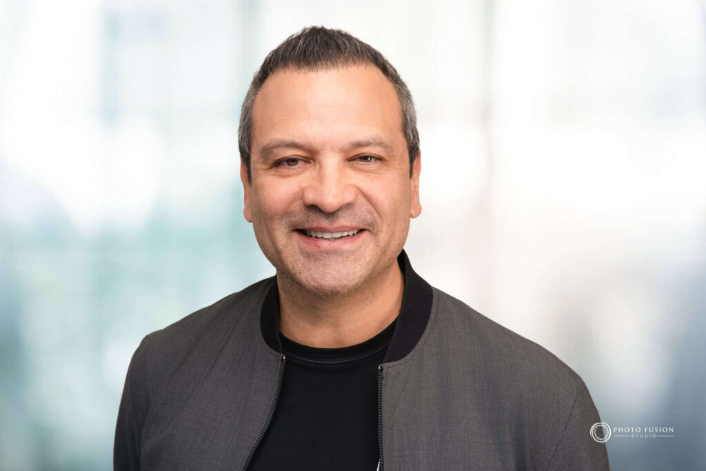Man smiling at the camera getting his headshot taken at a headshot station.
