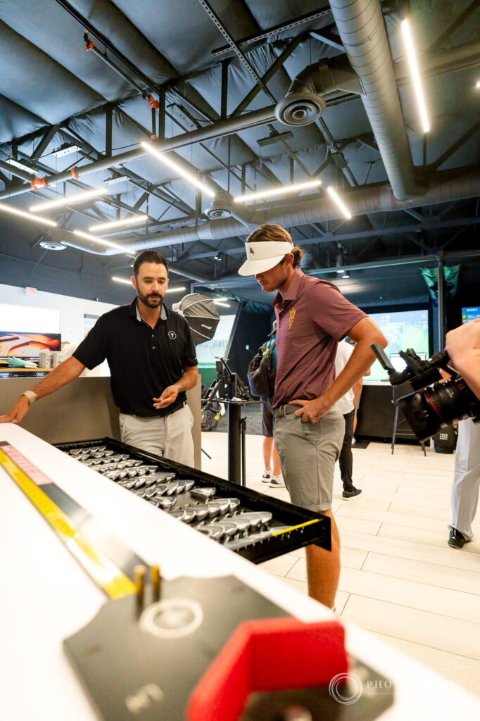 A True Spec Golf fitter opens a drawer of clubheads while an ASU golfer looks over the options