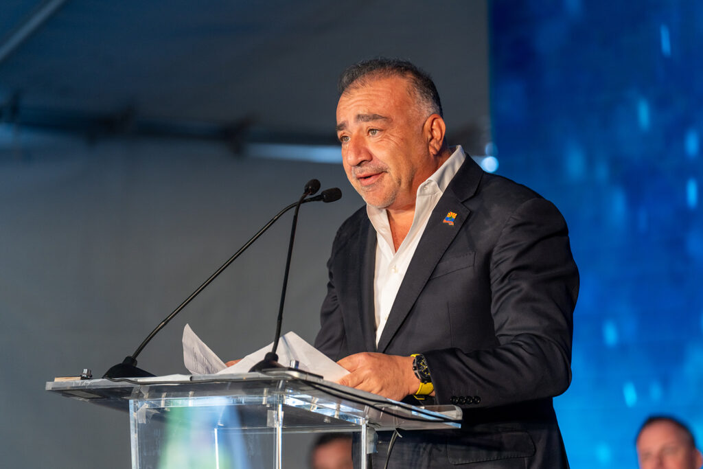 XNRGY CEO Wais Jalali delivering remarks from a clear podium during the ribbon cutting ceremony at the Mesa Gateway facility.