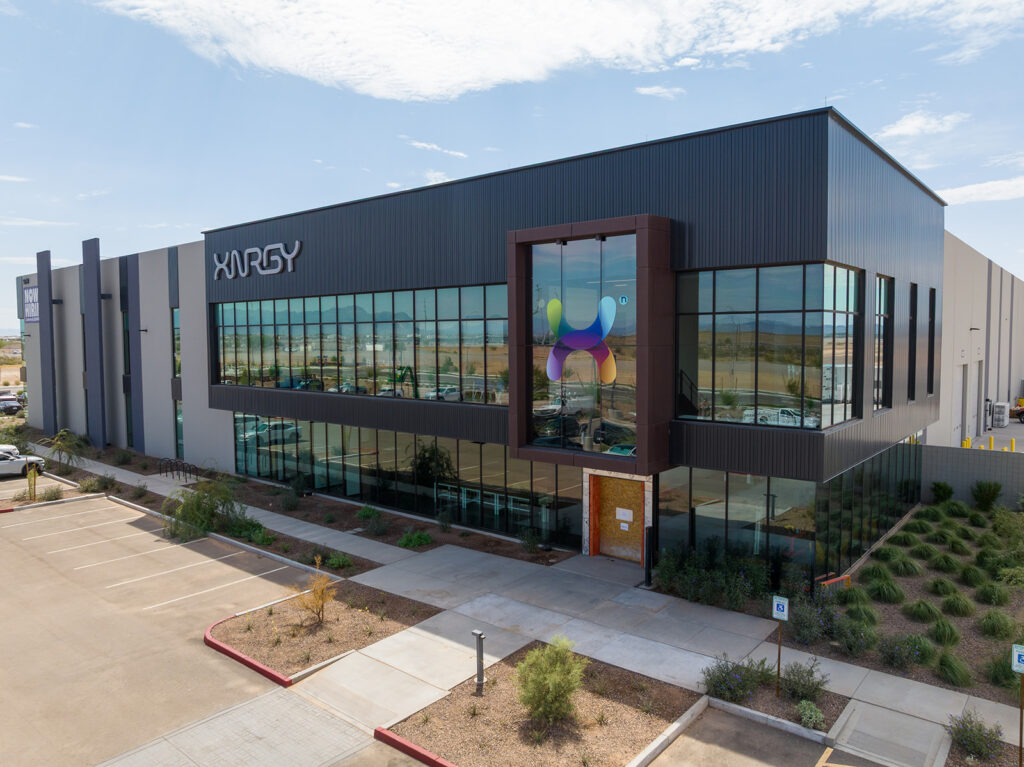 Aerial daytime view of XNRGY's new manufacturing facility entrance with signature colorful X art installation near Mesa Gateway Airport in Mesa, Arizona.