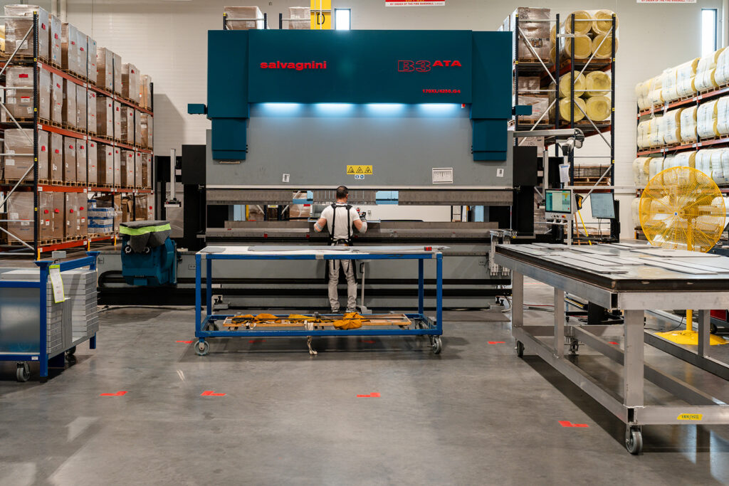 XNRGY operator working at a press brake bending sheet metal at the Mesa Gateway fabrication area.