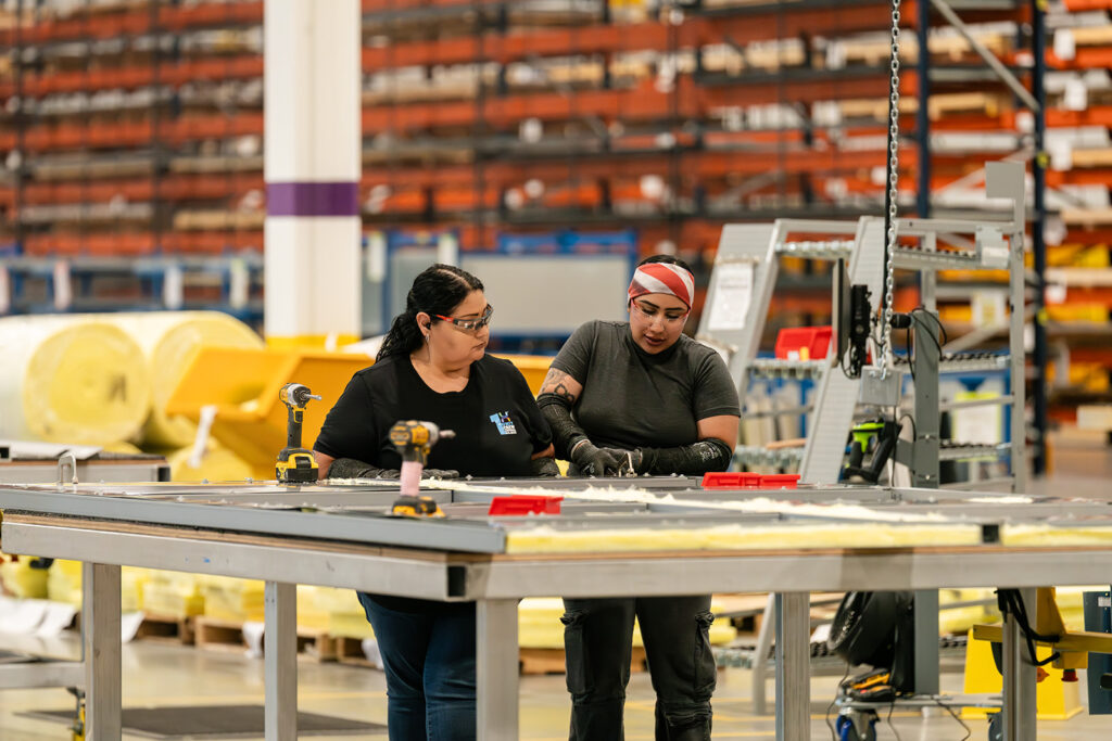 Two XNRGY technicians using cordless tools at an assembly table at the Mesa Gateway facility.