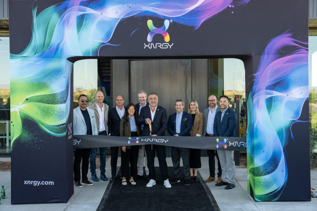 XNRGY CEO Wais Jalali and leadership team posed with ceremonial scissors at the ribbon cutting of the Mesa Gateway facility entrance arch.