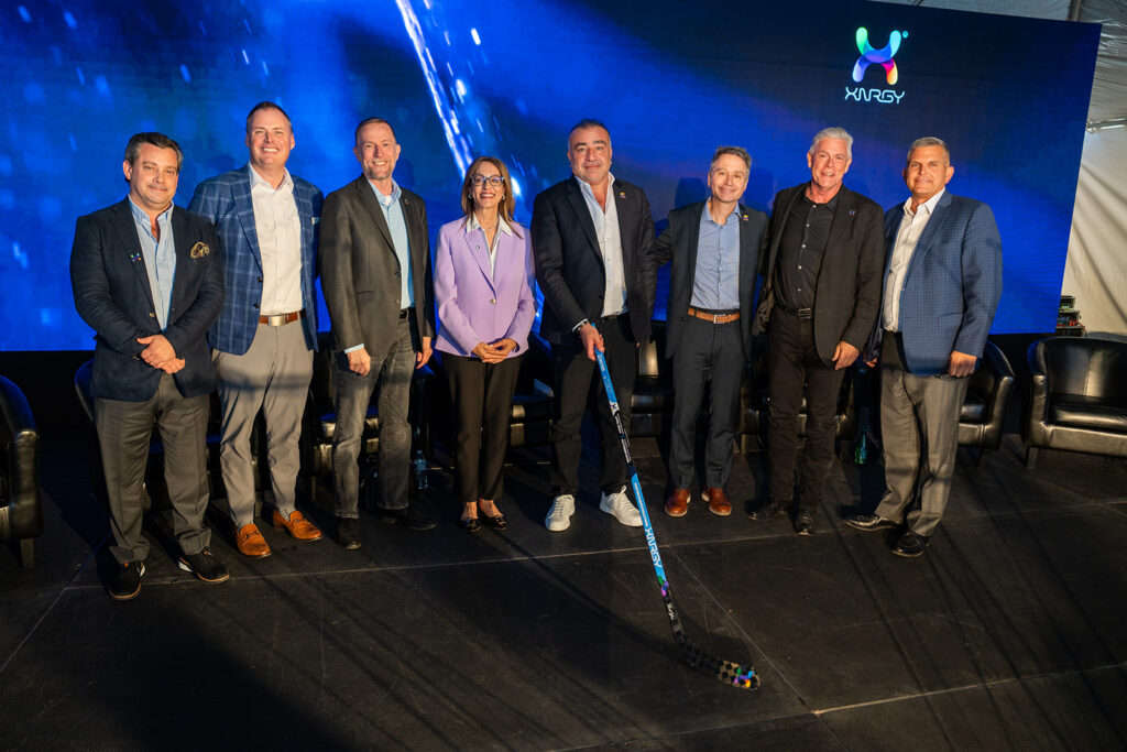 XNRGY CEO Wais Jalali with leadership and Arizona dignitaries posing on stage with a hockey stick during the ribbon cutting ceremony at the Mesa Gateway facility.