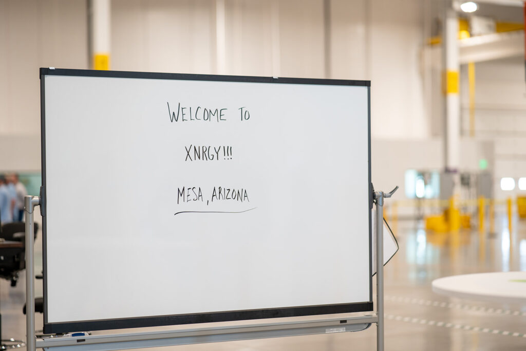 Whiteboard hand-lettered with WELCOME TO XNRGY!!! MESA, ARIZONA inside the new XNRGY Mesa Gateway facility on ribbon cutting day.